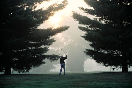 golfer swinging at sunrise